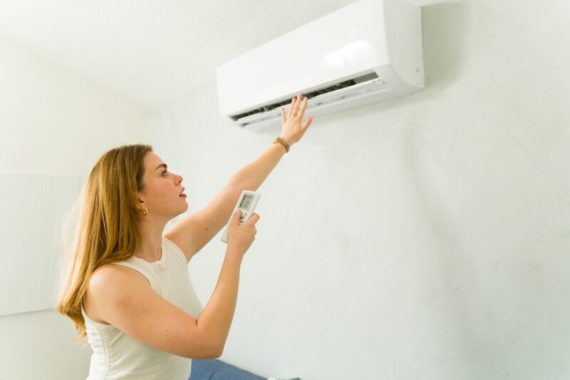 devojka pali klimu i proverava da li duva